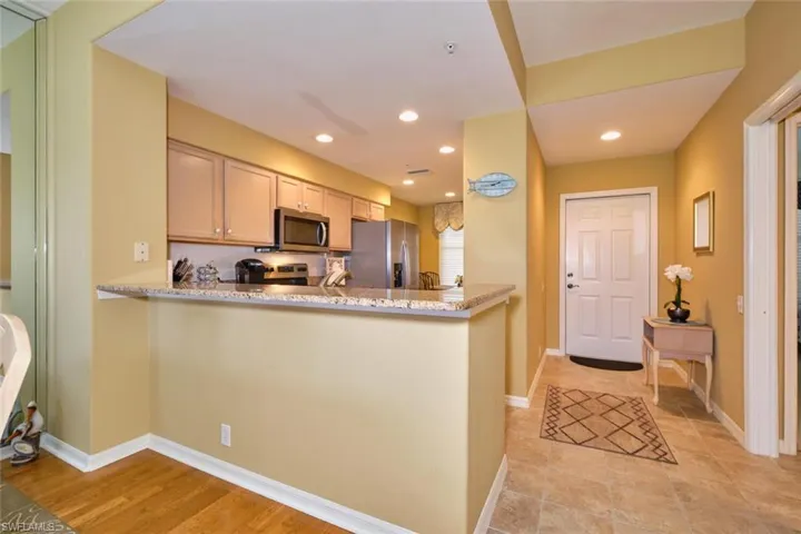 Kitchen with light stone countertops, appliances with stainless steel finishes, a peninsula, baseboards, and recessed lighting