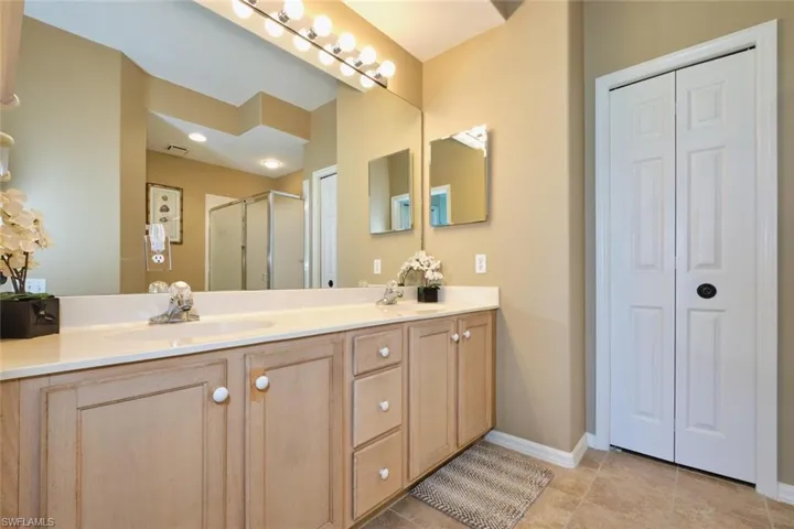 Bathroom featuring a closet, double vanity, a sink, and a shower stall
