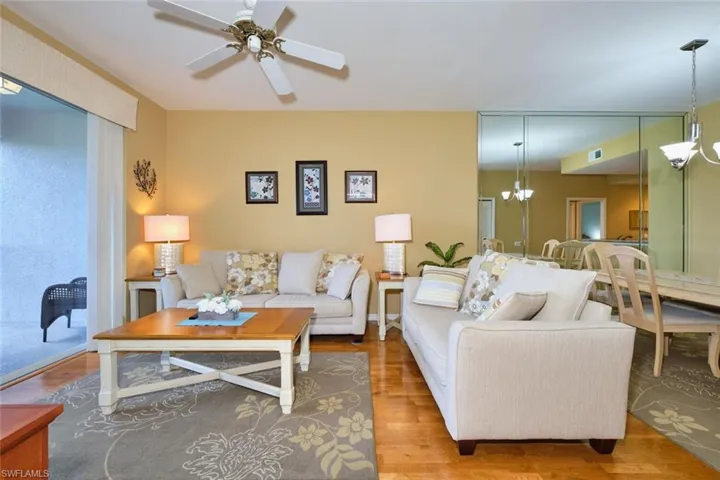 Living room featuring visible vents, wood finished floors, and ceiling fan with notable chandelier
