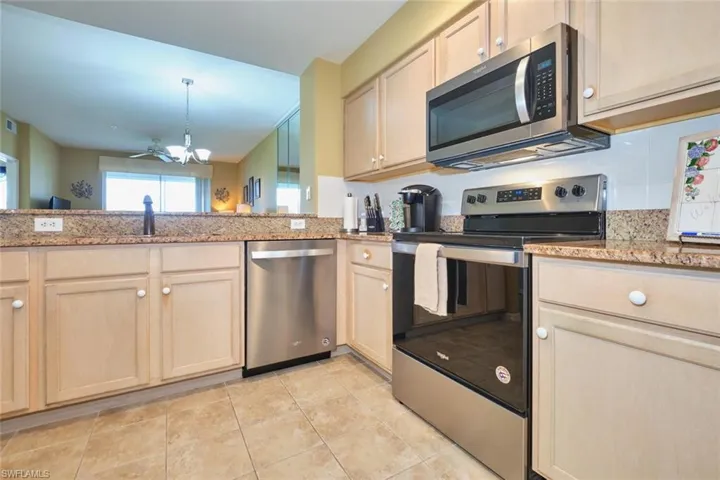 Kitchen with a notable chandelier, stainless steel appliances, light stone counters, backsplash, and light brown cabinetry