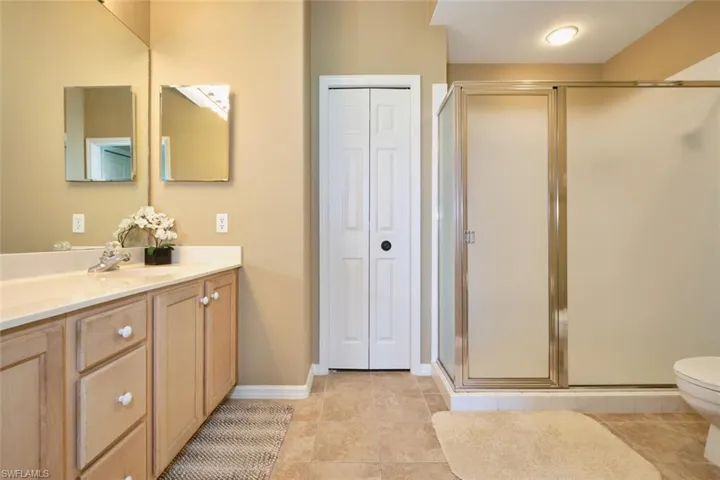 Bathroom with tile patterned flooring, vanity, toilet, a shower stall, and a closet
