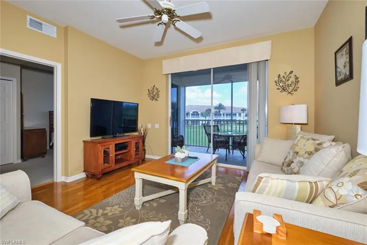 Living room with baseboards, visible vents, wood finished floors, and ceiling fan