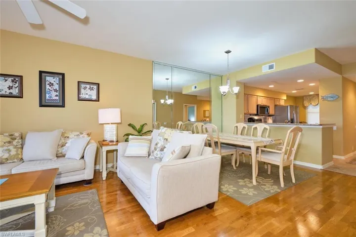 Living room with ceiling fan with notable chandelier, baseboards, light wood finished floors, and visible vents