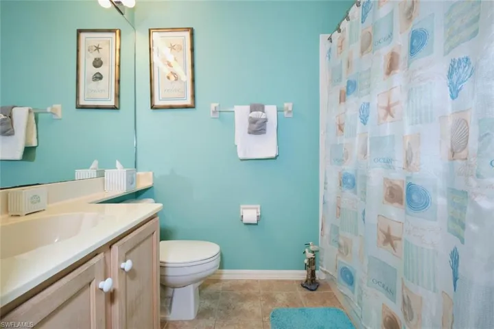 Full bathroom with toilet, vanity, tile patterned floors, and baseboards
