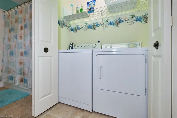 Laundry area with light tile patterned flooring, washing machine and dryer, and laundry area