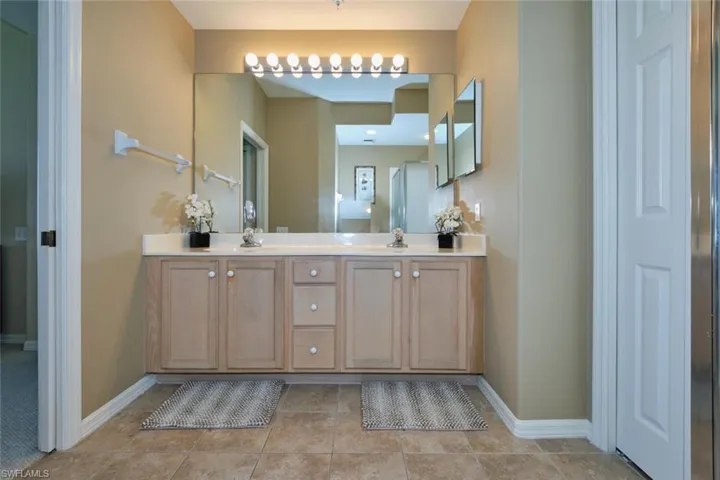 Full bathroom featuring baseboards, a sink, double vanity, and tile patterned floors