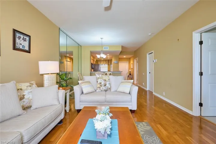 Living room with baseboards, visible vents, wood finished floors, and ceiling fan with notable chandelier