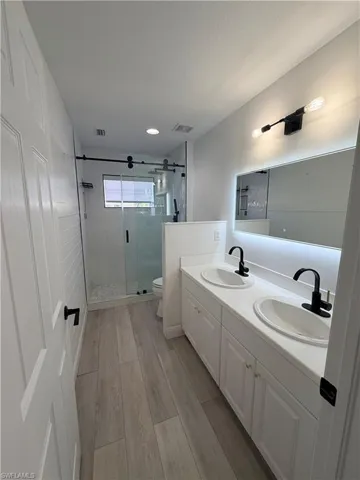 Unfurnished room featuring a raised ceiling, light wood-type flooring, and hanging lights