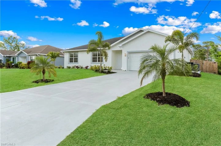 Ranch-style house featuring a front yard, fence, concrete driveway, an attached garage, and stucco siding