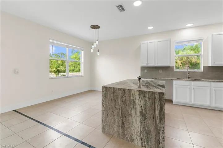 Kitchen with backsplash, visible vents, light stone countertops, a sink, and light tile patterned flooring