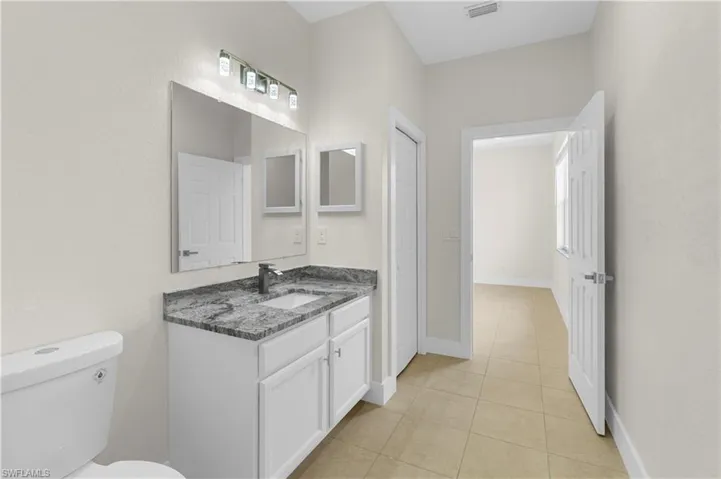 Bathroom featuring visible vents, vanity, toilet, baseboards, and tile patterned floors