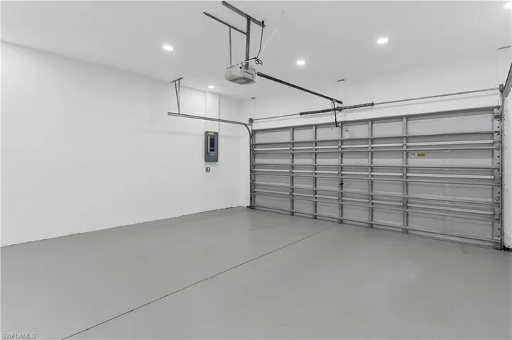 Garage featuring a garage door opener, electric panel, and recessed lighting
