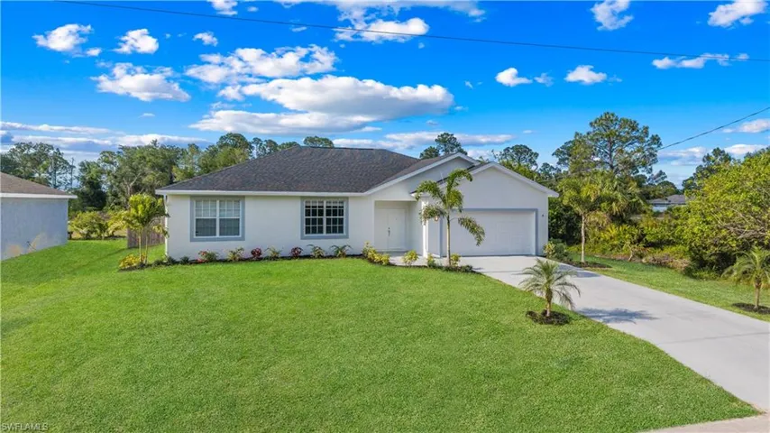 Ranch-style home with a garage, a front lawn, stucco siding, and concrete driveway
