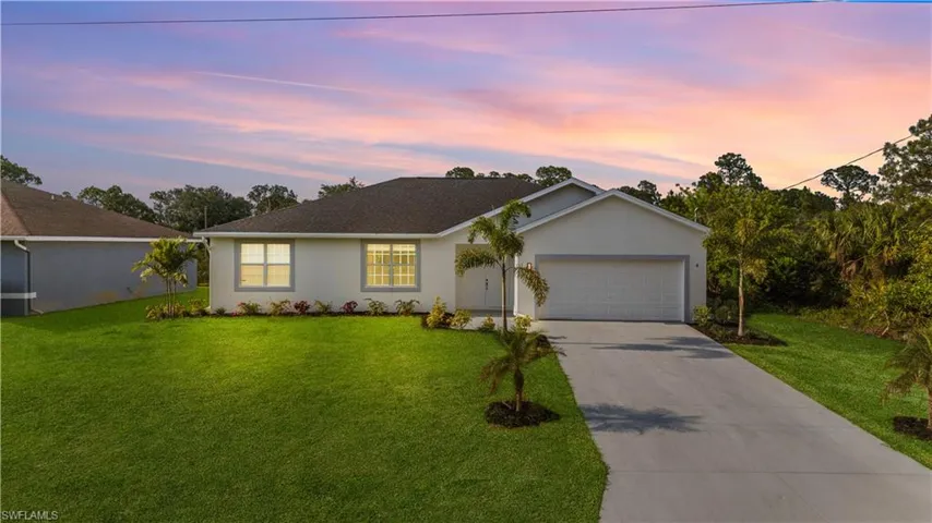 Single story home featuring a lawn, stucco siding, driveway, and a garage