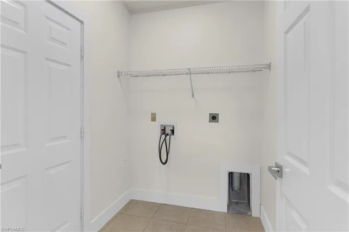 Clothes washing area featuring laundry area, hookup for a washing machine, baseboards, light tile patterned floors, and hookup for an electric dryer