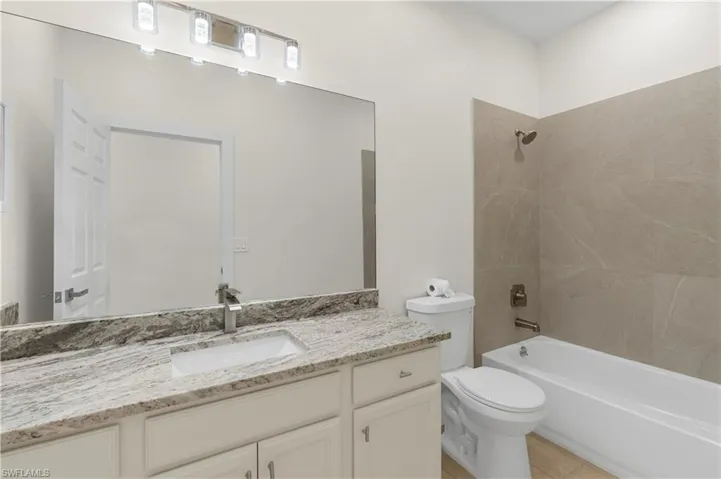 Full bath featuring shower / bath combination, tile patterned flooring, toilet, and vanity