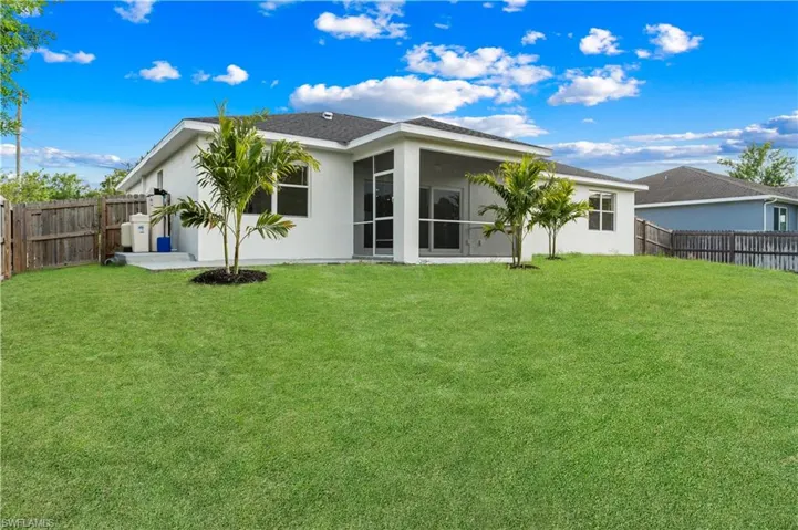Rear view of property with a fenced backyard, stucco siding, and a yard