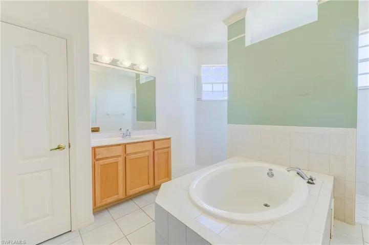 Bathroom featuring a bath, vanity, and tile patterned flooring