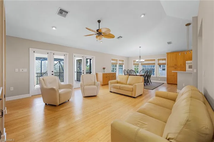 Living room with lofted ceiling, ceiling fan, french doors, and wood-type flooring