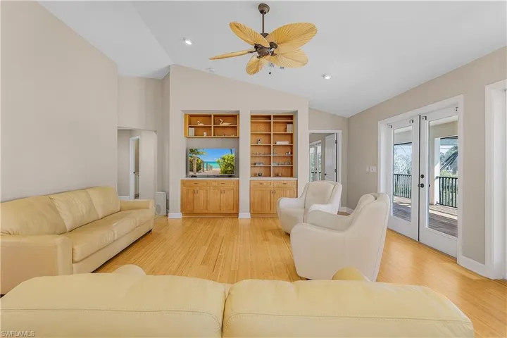 Living room with french doors, ceiling fan, lofted ceiling, and light hardwood / wood-style flooring