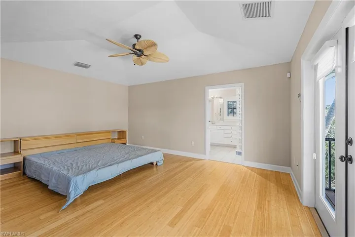 Bedroom with wood-style flooring, ceiling fan, lofted ceiling, and ensuite bathroom