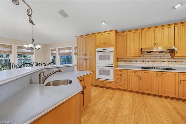 Kitchen with sink, double oven, hanging light fixture, and cooktop
