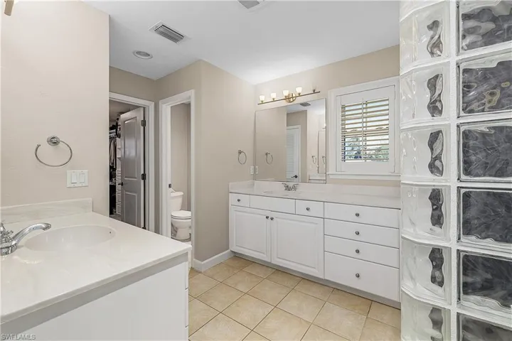 Bathroom featuring tile patterned flooring, vanities, and toilet closet