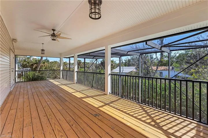 Wooden deck featuring a ceiling fan and screened enclosure