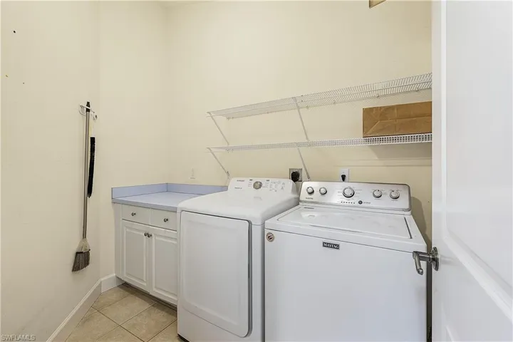 Washroom with cabinets, shelving, and washer and dryer