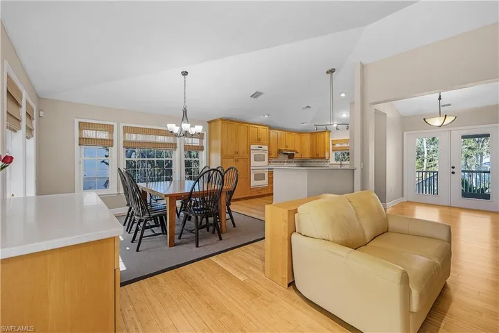 Living room featuring french doors, a notable chandelier, lofted ceiling, and light wood-type flooring