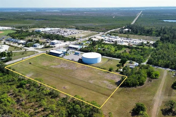 Expansive cleared lot outlined in yellow, featuring direct frontage on a paved road