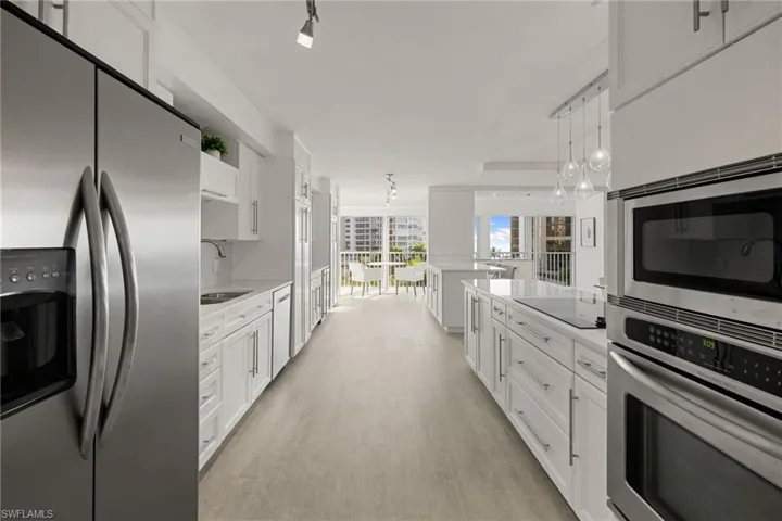 Kitchen with stainless steel appliances, white cabinetry, and decorative light fixtures