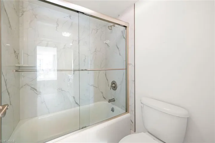 Full bath featuring shower / bath combination with glass door and toilet