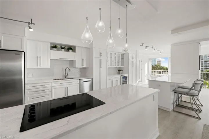Kitchen featuring stainless steel appliances, rail lighting, white cabinetry, backsplash, and light stone countertops