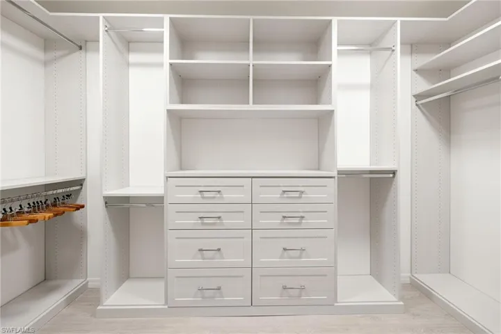 Walk in closet with light wood finished floors