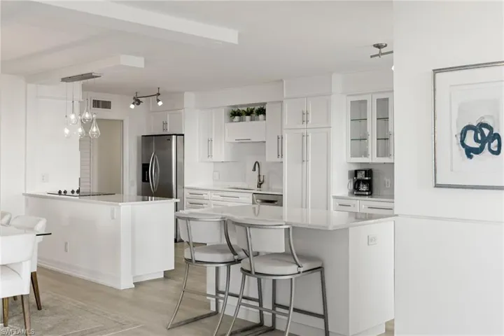 Kitchen with a kitchen breakfast bar, pendant lighting, white cabinets, a peninsula, and light wood-type flooring