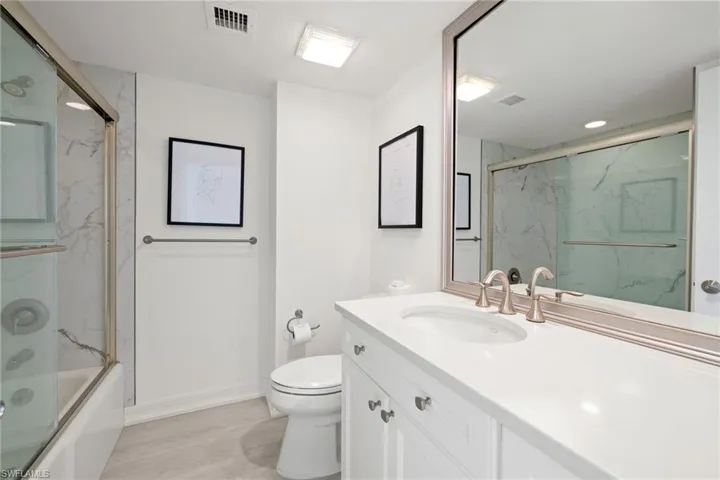 Bathroom with vanity and enclosed tub / shower combo