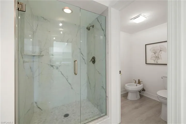 Bathroom featuring a bidet, a marble finish shower, and wood finished floors
