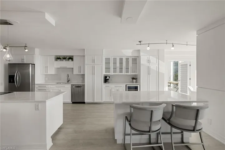 Kitchen featuring track lighting, a kitchen breakfast bar, white cabinets, stainless steel appliances, and a kitchen island