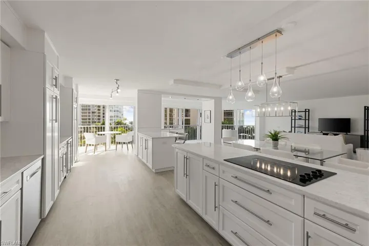 Kitchen with white cabinets, light stone counters, open floor plan, black electric stovetop, and dishwasher