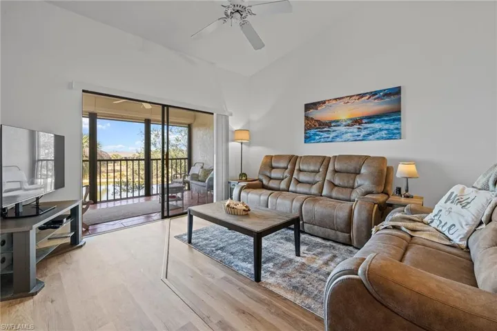 Living room with high vaulted ceiling, light hardwood / wood-style floors, and ceiling fan