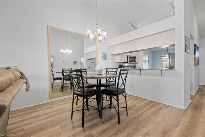 Dining area featuring a notable chandelier, track lighting, high vaulted ceiling, and light hardwood / wood-style floors
