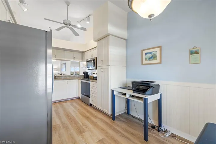 Kitchen with ceiling fan, stainless steel appliances, white cabinets, and light wood-type flooring