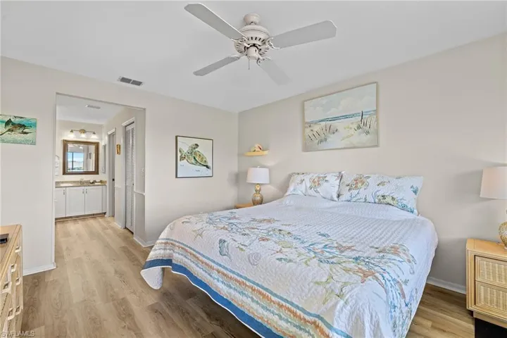 Bedroom with ceiling fan, ensuite bathroom, light wood-type flooring, and a closet
