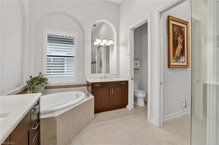 Featuring his and hers vanities, soaking tub, plantation shutters, and window with impact hurricane glass