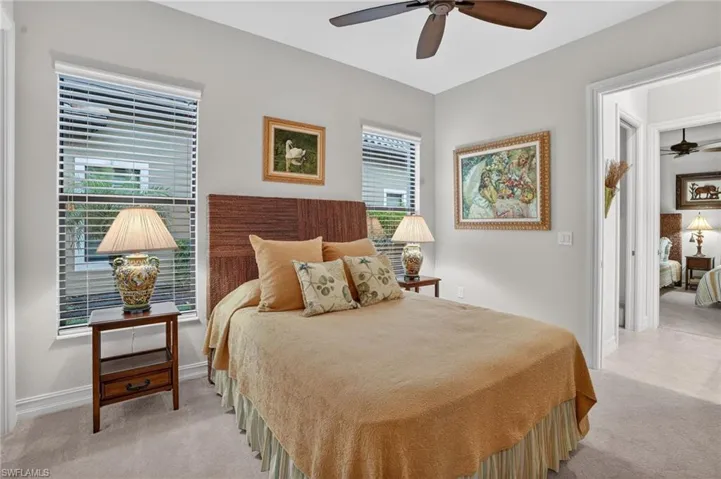 Featuring light carpet, windows with hurricane impact glass, ceiling fan, and view of adjacent guest bedroom. Both guest bedrooms have access to the bathroom (Jack and Jill bathroom type)