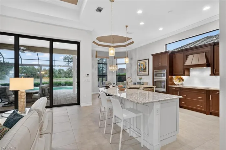 Featuring pendent light fixtures, premium wood kitchen cabs, premium range hood, island bar, and great views of the lake and water feature