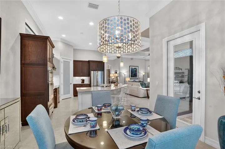 Eat-in eating area with a chandelier, ornamental molding, recessed lighting, ceiling fan, and impact glass door to the lanai