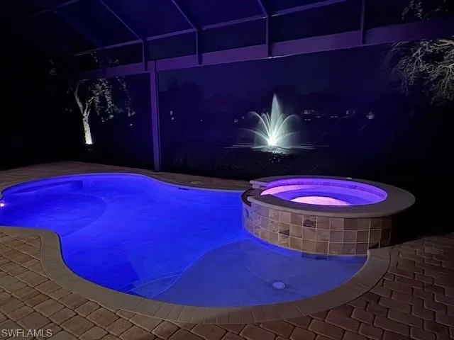 Evening lake view of illuminated fountain, custom-color pool lighting  and spa, and night scaped landscape lighting on all trees