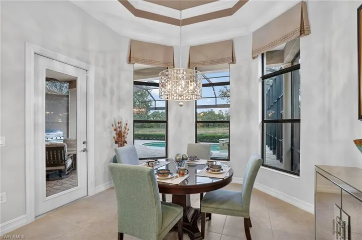Kitchen eating  area with crown molding,  a tray ceiling w/ Chandellar, door to lanai, and bay window